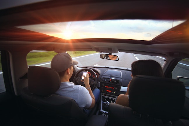 Couple driving while using cell phone, Driver using phone to navigate while driving.